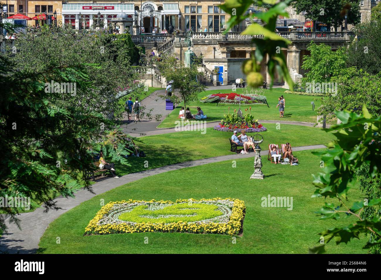 Leute, die sich entspannen und Bücher lesen in Parade Gardens, Bath, Großbritannien. Sie genießen die friedliche Atmosphäre und die malerische Aussicht im öffentlichen Park. Stockfoto