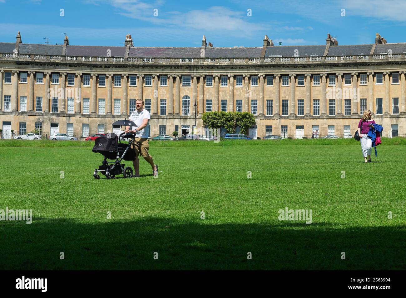 Die Menschen sind zu Fuß vor dem Royal Crescent in Bath, Großbritannien, zu sehen und genießen das warme Wetter, die malerische Aussicht und die historische georgianische Architektur. Stockfoto