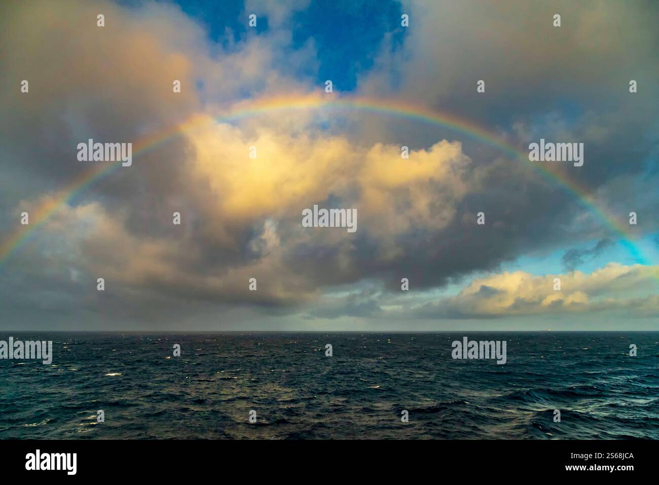 Regenbogen im Atlantischen Ozean am frühen Morgen, verursacht durch Sonnenlicht, das durch Regentropfen fließt. Stockfoto