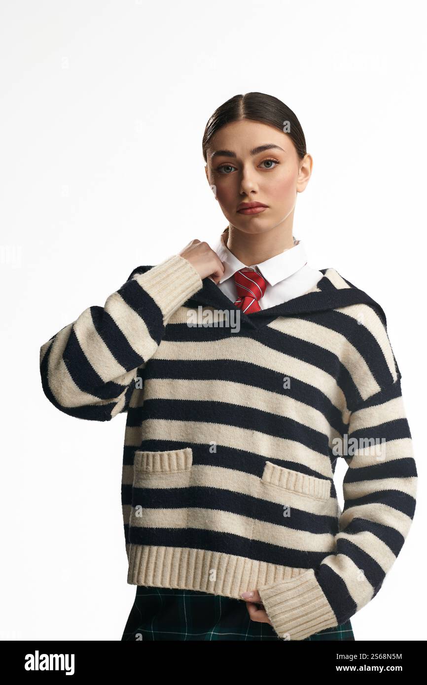 Eine junge, schöne Frau mit einem gestreiften Pullover sieht nachdenklich mit einem ernsten Ausdruck aus. Stockfoto