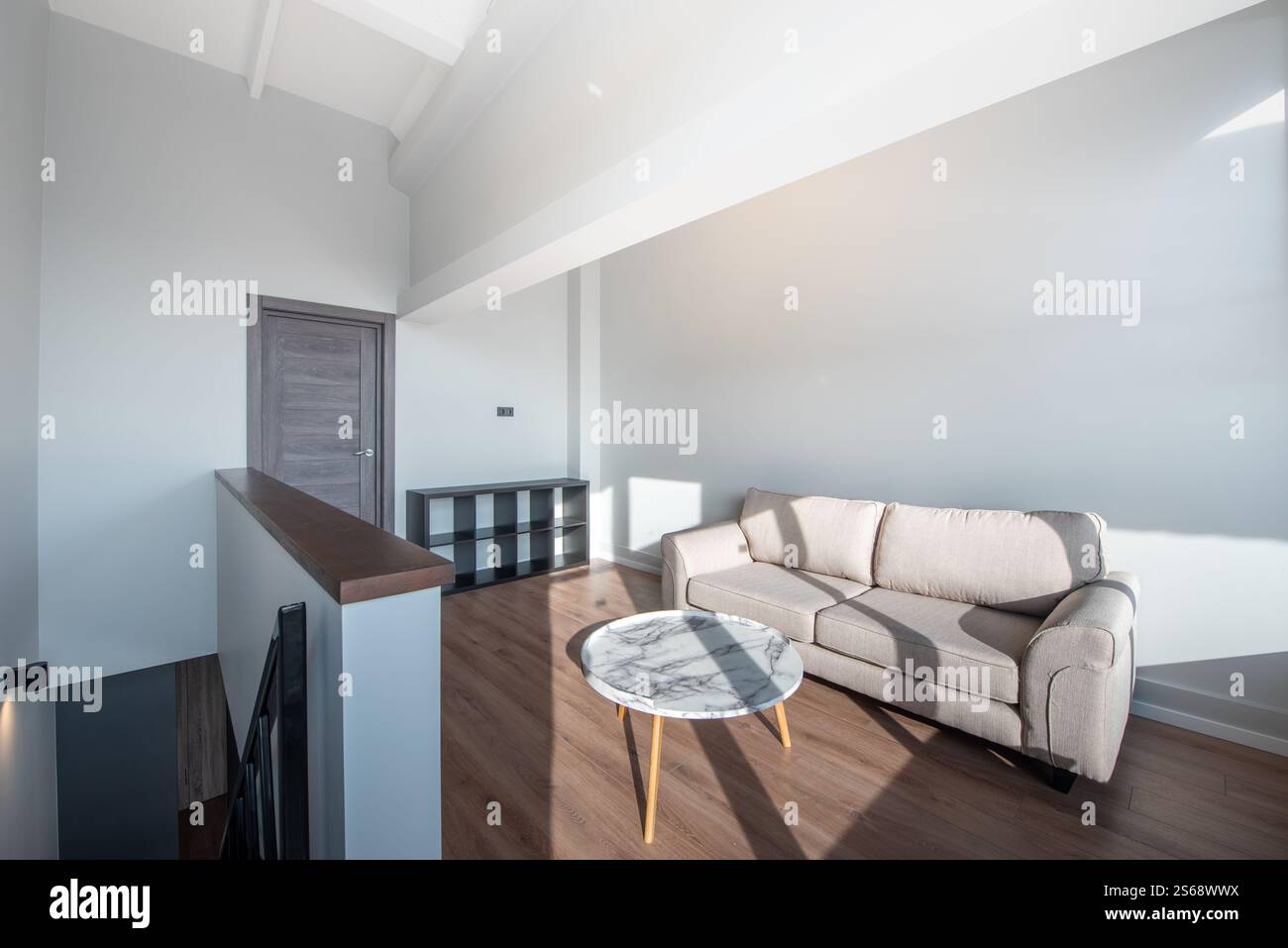 Heller, moderner Wohnbereich mit komfortablem Sofa, rundem Marmortisch, Naturholzboden und skandinavischem Design. Saubere Architektur Stockfoto