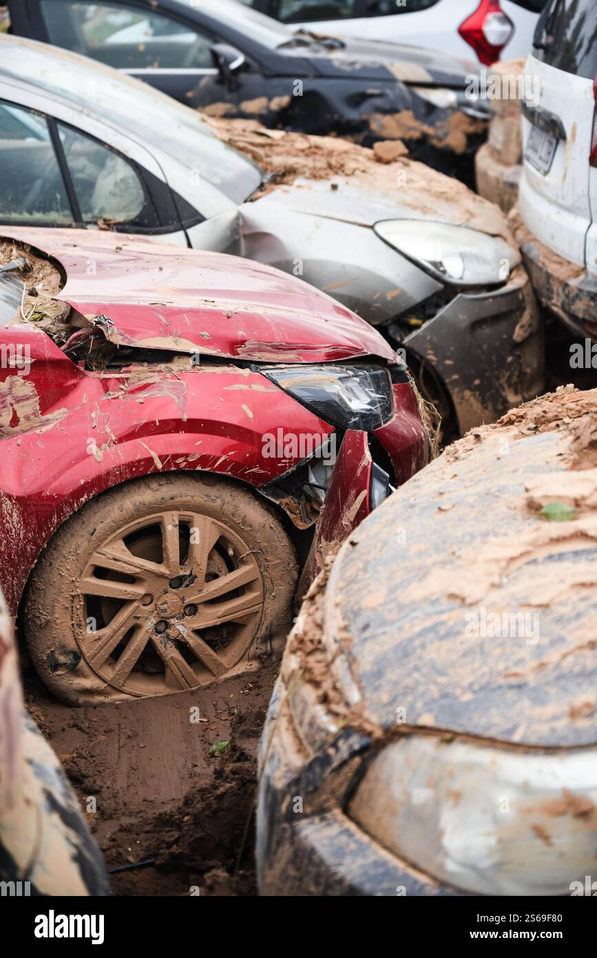 Zerstörte Autos, die mit Dreck bedeckt sind, stecken im Schlamm auf dem Parkplatz. DANA Flooding, Spanien. Stockfoto