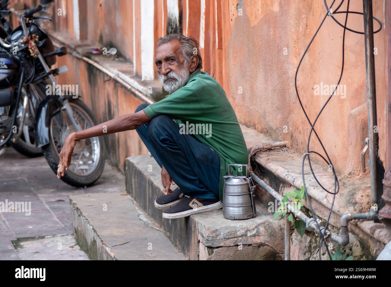 Indischer Mann auf der Straße auf seinen Spuren mit einem Tiffin-Behälter in Jaipur, Indien. Stockfoto