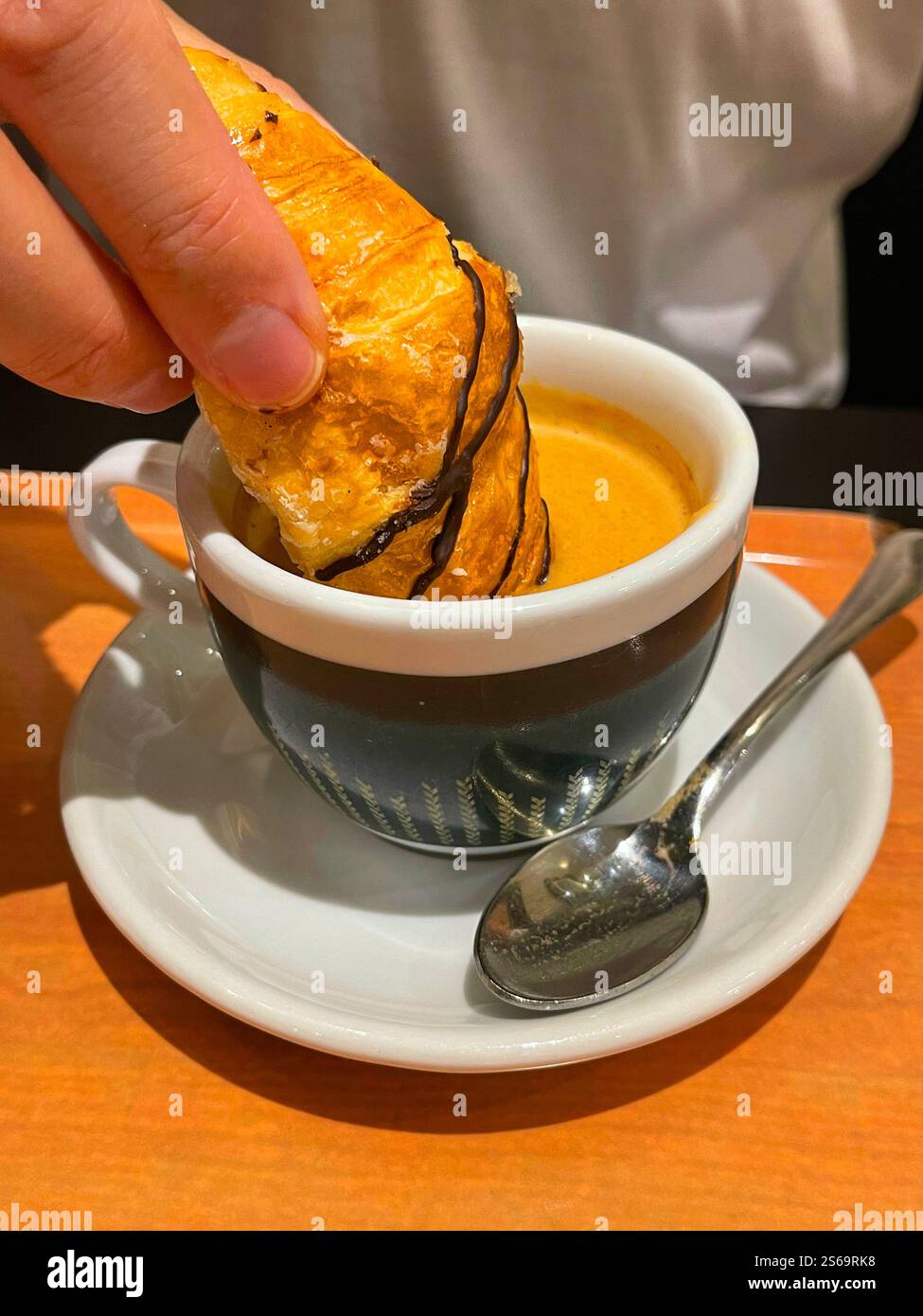 Tauche einen Kuchen von Hand in eine Tasse Kaffee. Stockfoto