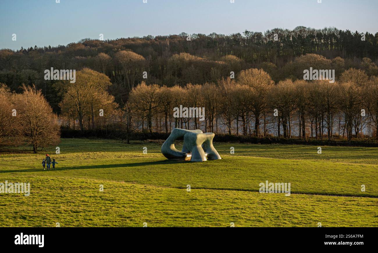 Henry Moores „zwei große Formen“ warf lange Schatten in der Nachmittagssonne und überragte einen Mann und seine zwei kleinen Kinder in der Yorkshire Sculpture. Stockfoto