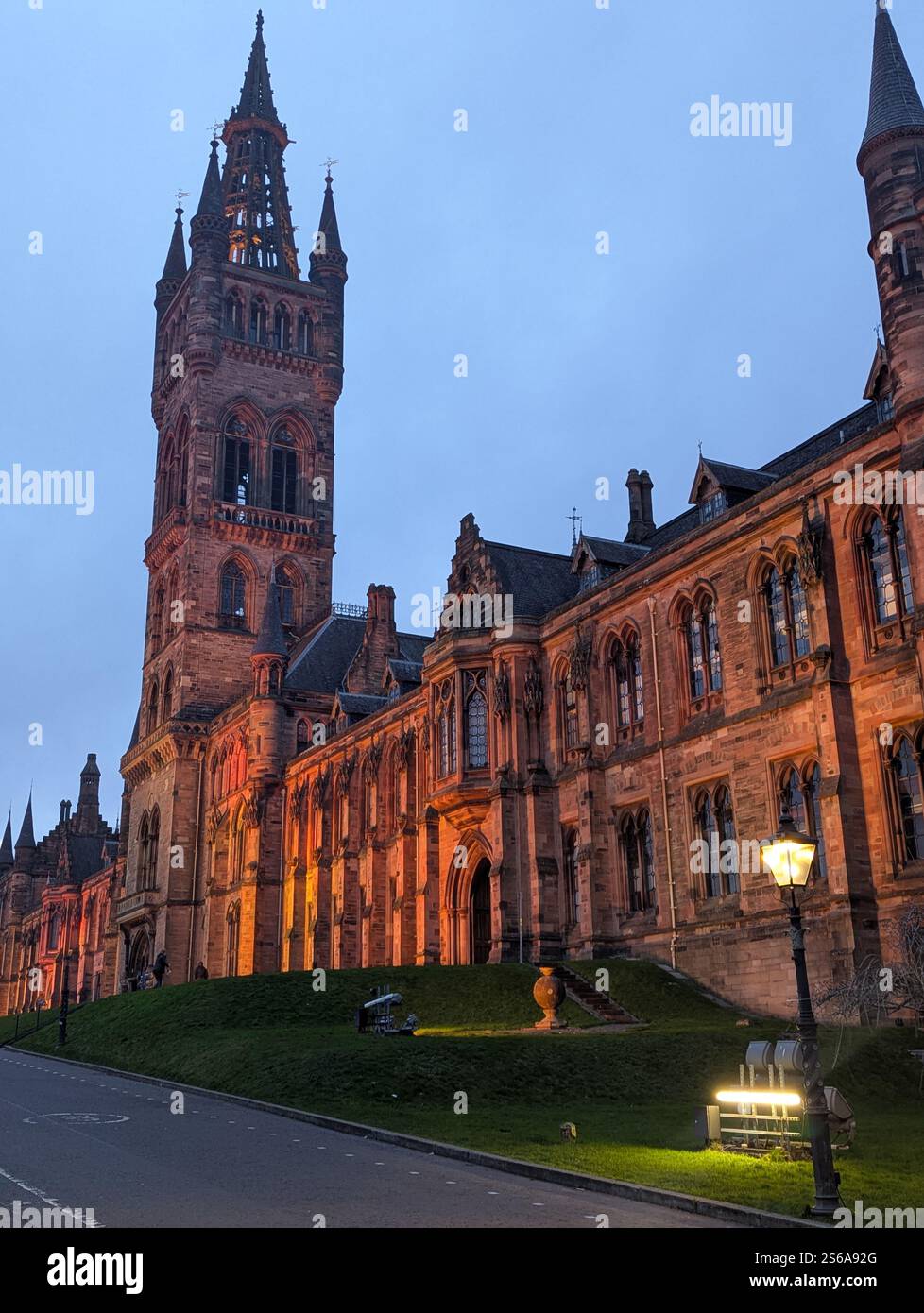 Ein atemberaubender Abendblick auf die historische Universität von Glasgow, wunderschön beleuchtet mit warmen Lichtern vor dem Dämmerungshimmel. Stockfoto