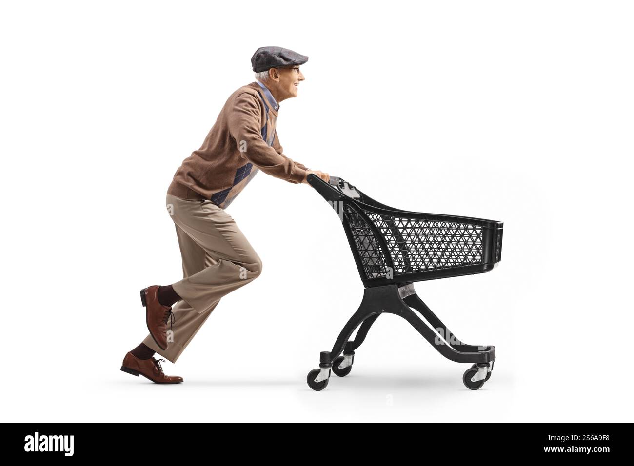 Profilaufnahme eines Rentners in voller Länge, der mit einem leeren Einkaufswagen auf weißem Hintergrund läuft Stockfoto