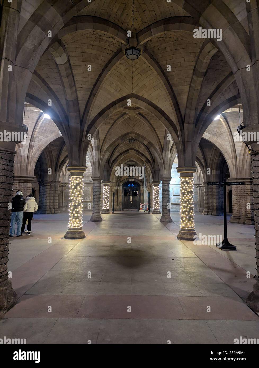 Gotische Bögen, die mit Feenlichtern beleuchtet sind, schaffen ein warmes und bezauberndes Ambiente an der University of Glasgow. Stockfoto