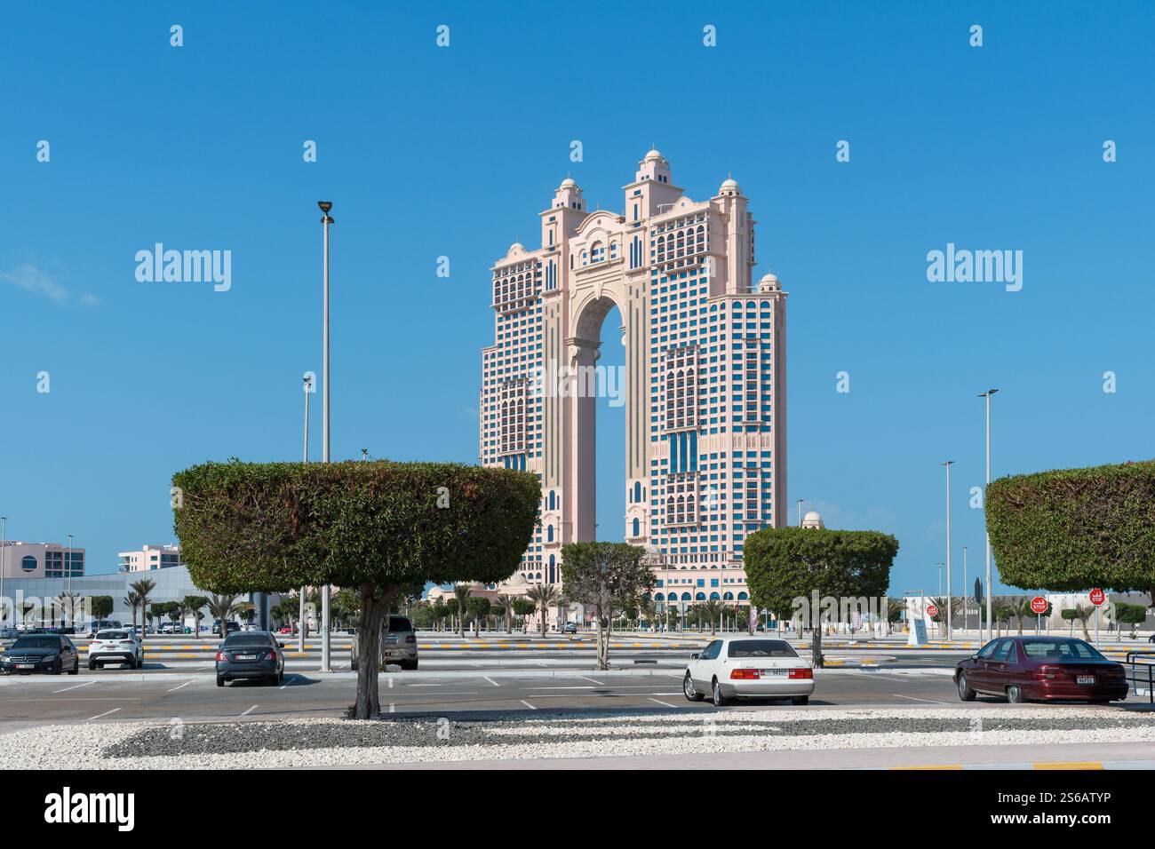 Abu Dhabi, VAE - 3. Januar 2025: Ein Blick auf die berühmten Gate Towers, ein prominentes architektonisches Wahrzeichen der Stadt, mit sauber geschnittenen Bäumen und Autos Stockfoto