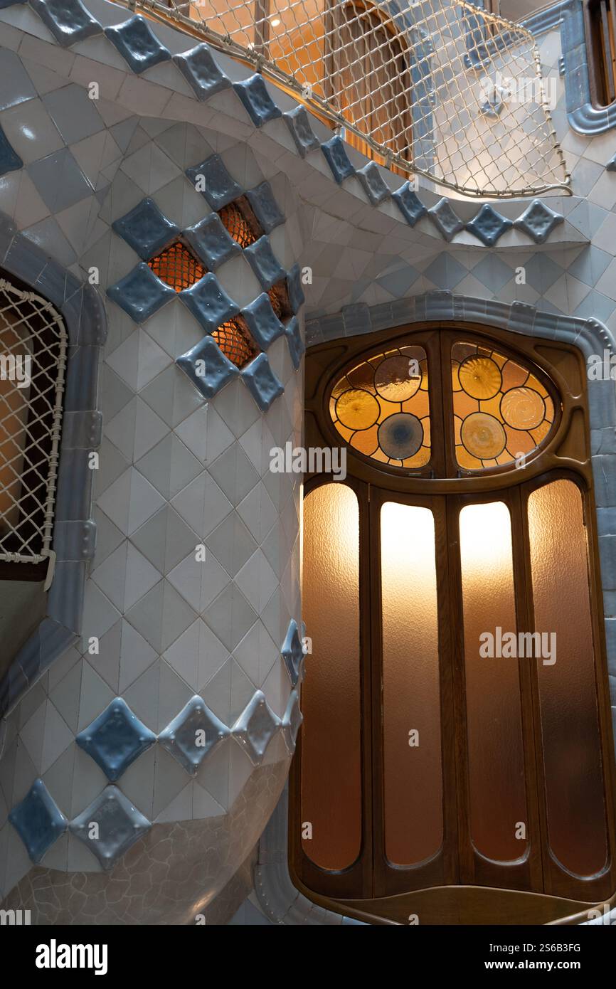 Nahaufnahme eines Fensters und einer Wand in der Innentreppe der Casa Batlló, wo Blautöne die ruhigen Tiefen des Ozeans durch das Design von Gaudí erinnern. Stockfoto