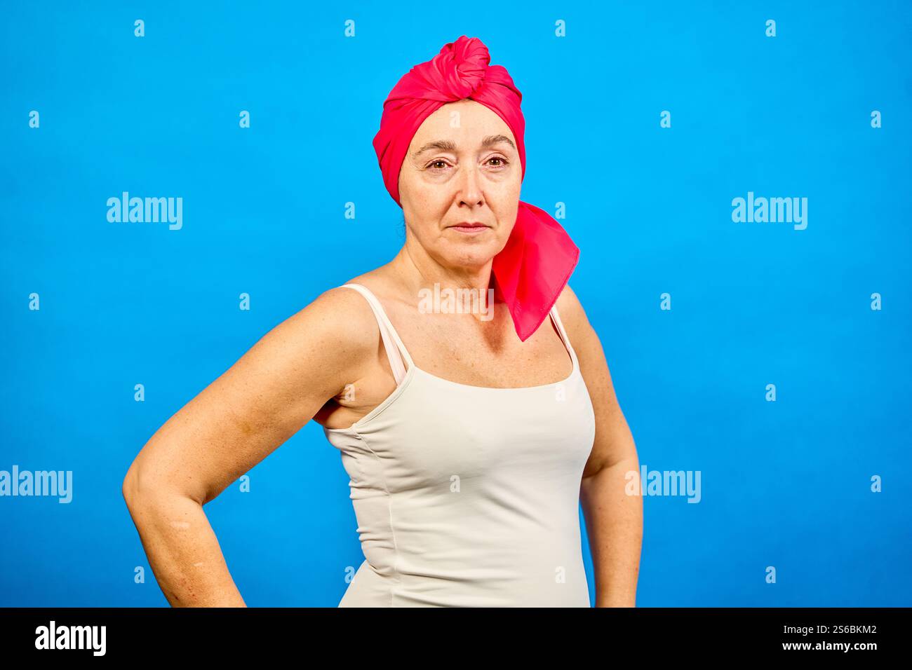 Porträt einer Frau mittleren Alters, die ein rosafarbenes Kopftuch trägt, symbolisiert ihren Kampf gegen Krebs, zeigt Stärke und Widerstandsfähigkeit Stockfoto