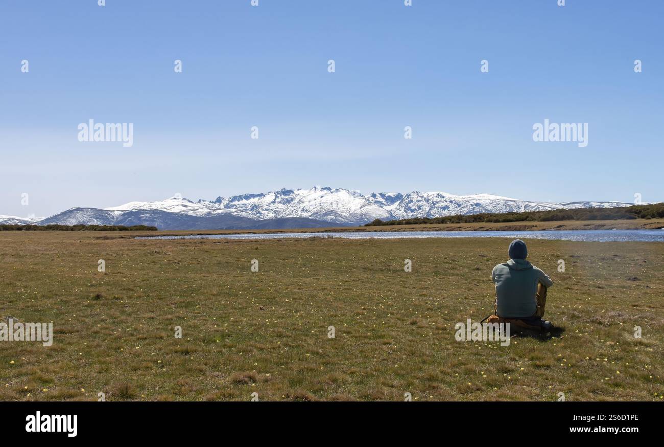 Person, die eine schneebedeckte Bergkette vor einem Bergsee betrachtet Stockfoto