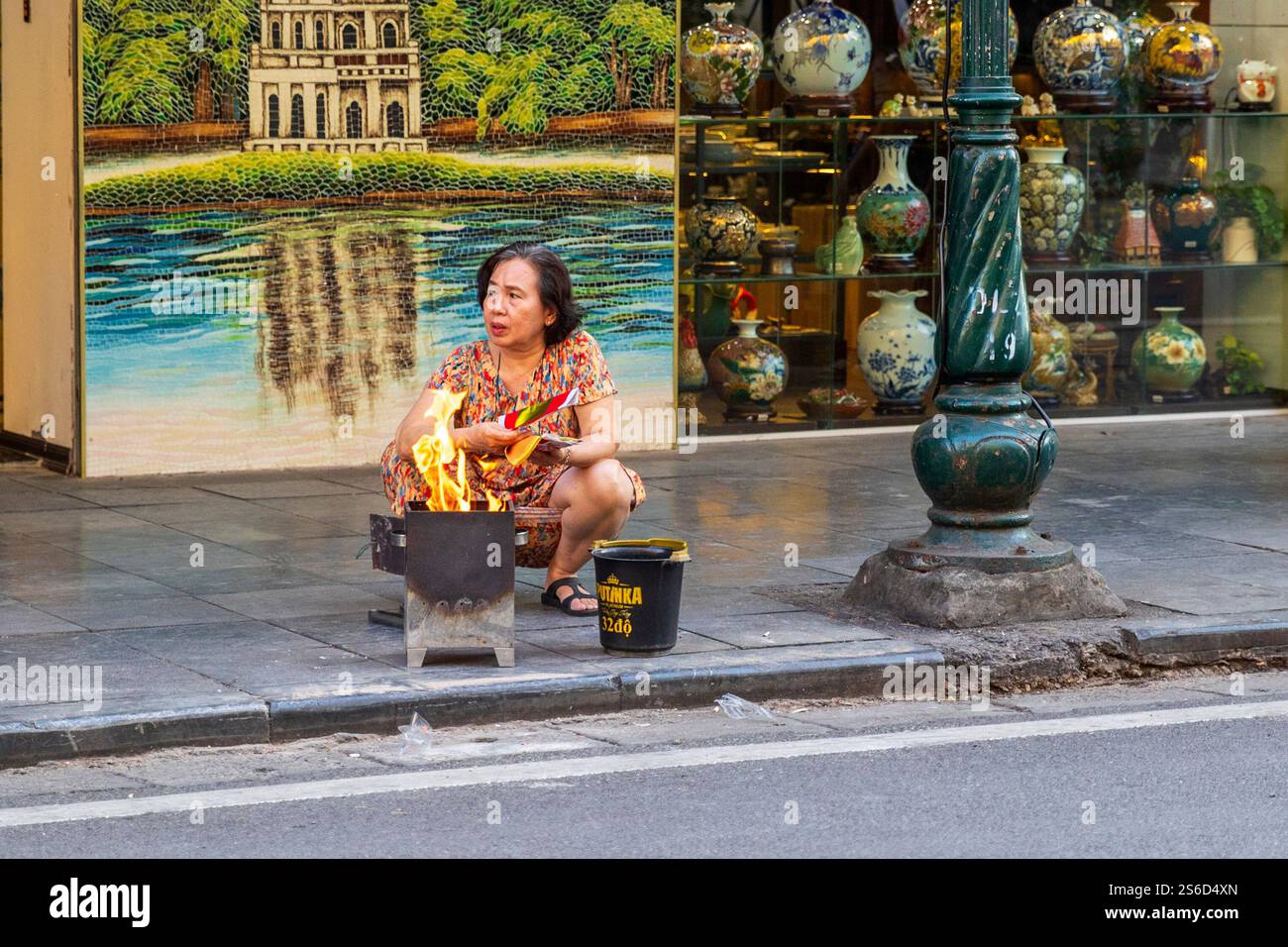 Frau brennt Joss Papier, ein traditionelles Ritual auf einer Straße, Hanoi, Vietnam, Freitag, 1. November, 2024. Foto: David Rowland / One-Image.com Stockfoto