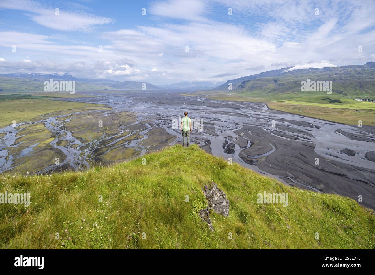 Wanderer, junger Mann auf einem Hügel, Blick über Schwemmland, mäandernden Fluss, Dimonarhellir, SuÃ°urland, Island, Europa Stockfoto