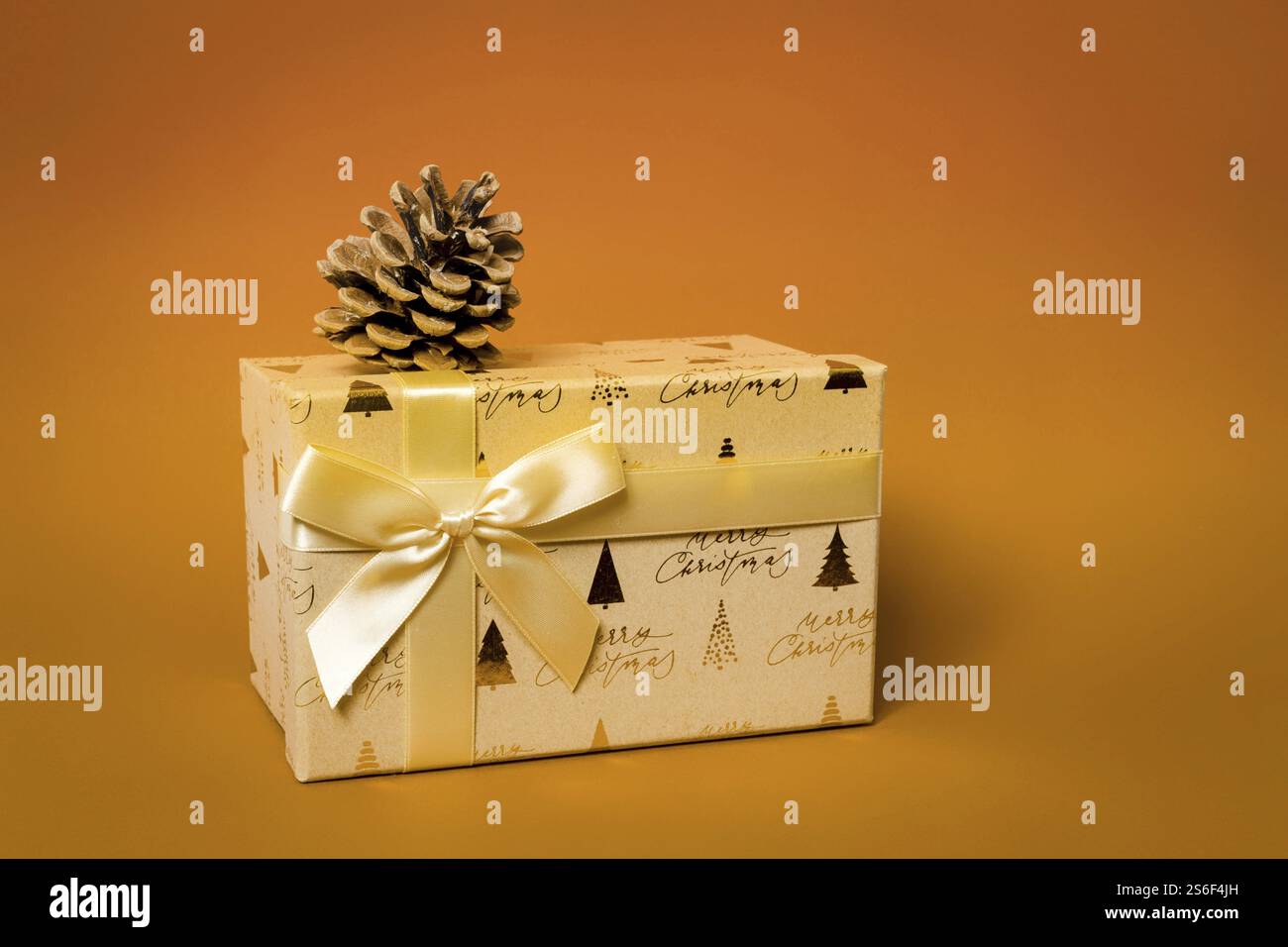 Eine goldene Weihnachts-Geschenkbox auf orangem Hintergrund Stockfoto