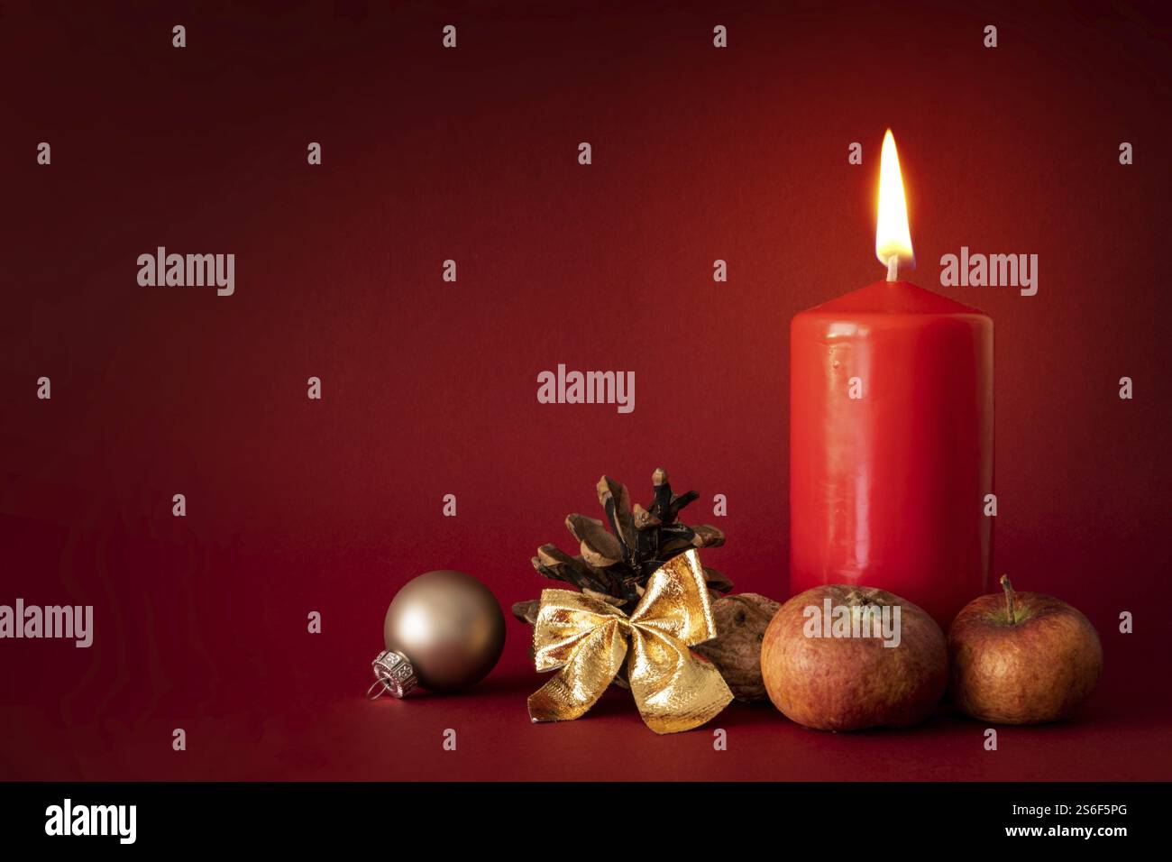 Weihnachtsdekoration mit einer brennenden Kerze auf rotem Hintergrund Stockfoto