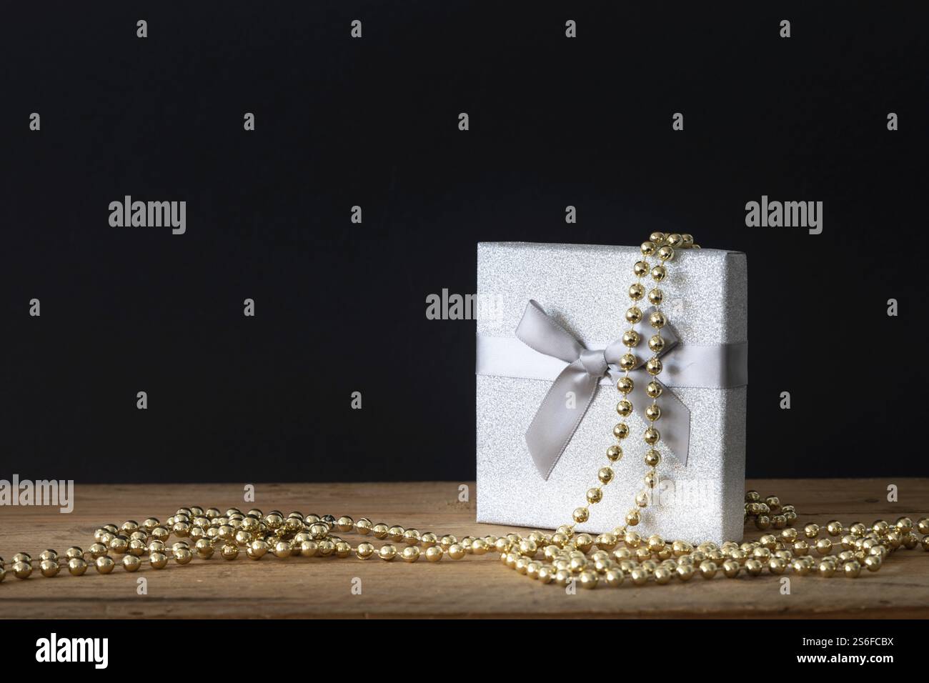 Eine Weihnachtsdekoration Geschenkbox mit goldenen perlen auf schwarzem Hintergrund Stockfoto