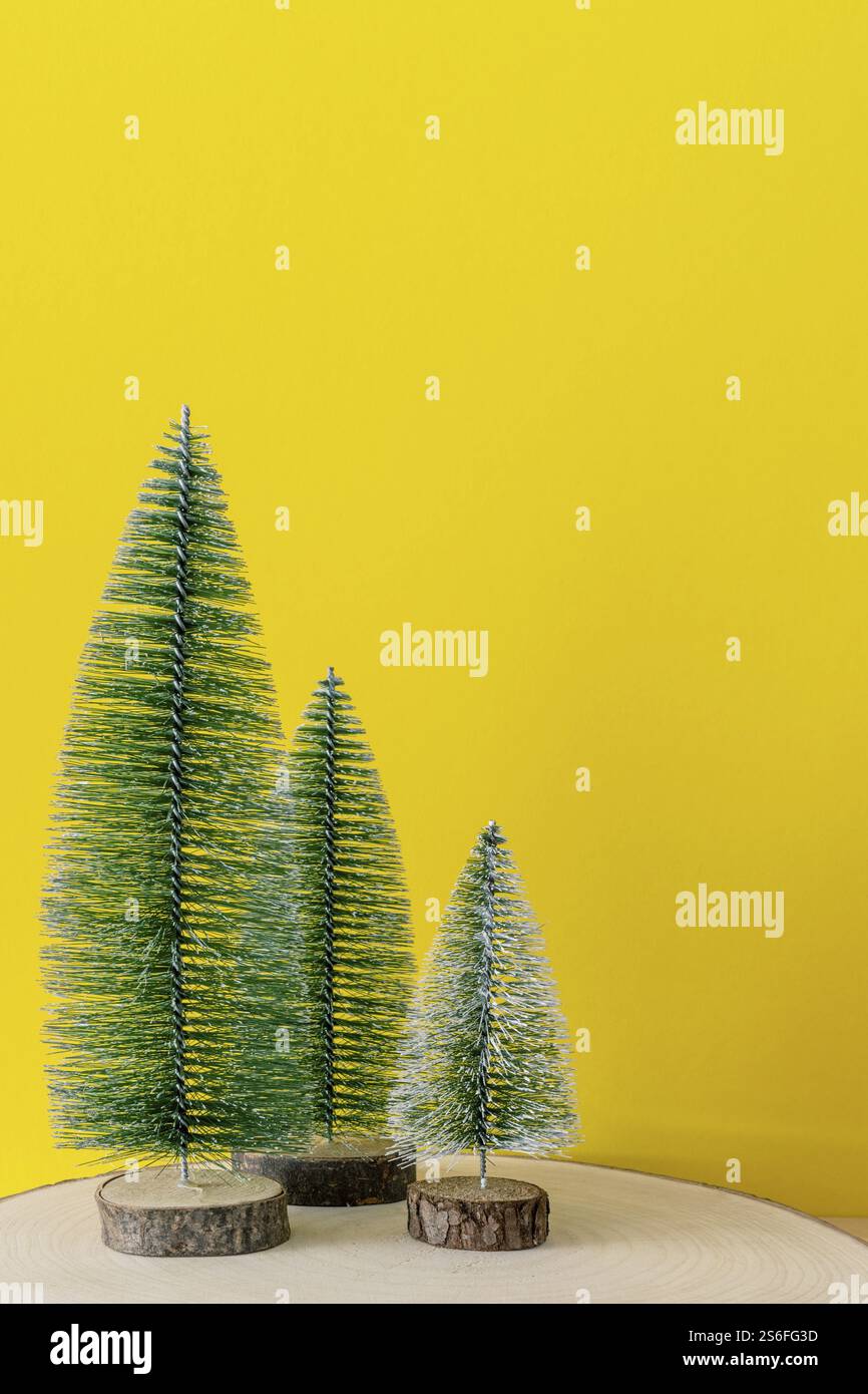Weihnachtsdekoration Drei Tannen vor einem gelben Hintergrund Stockfoto