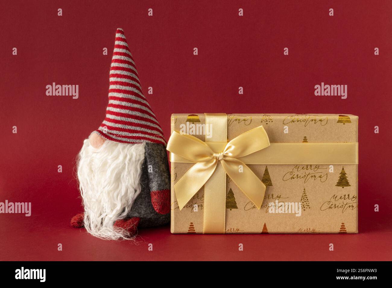 Weihnachtsdekoration mit einem gnome und einem Geschenkkarton auf rotem Hintergrund Stockfoto