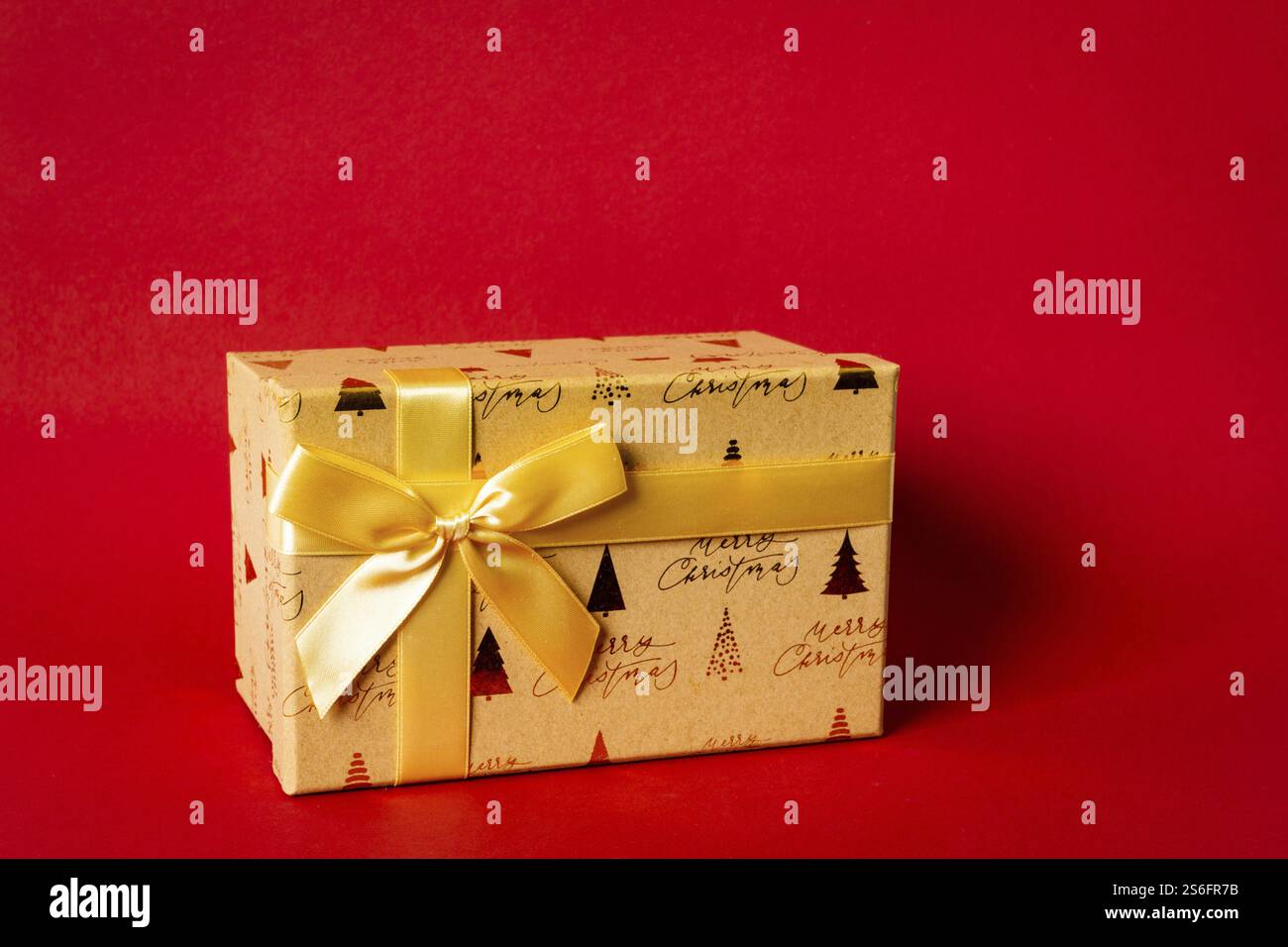 Eine goldene Weihnachts-Geschenkbox auf rotem Hintergrund Stockfoto
