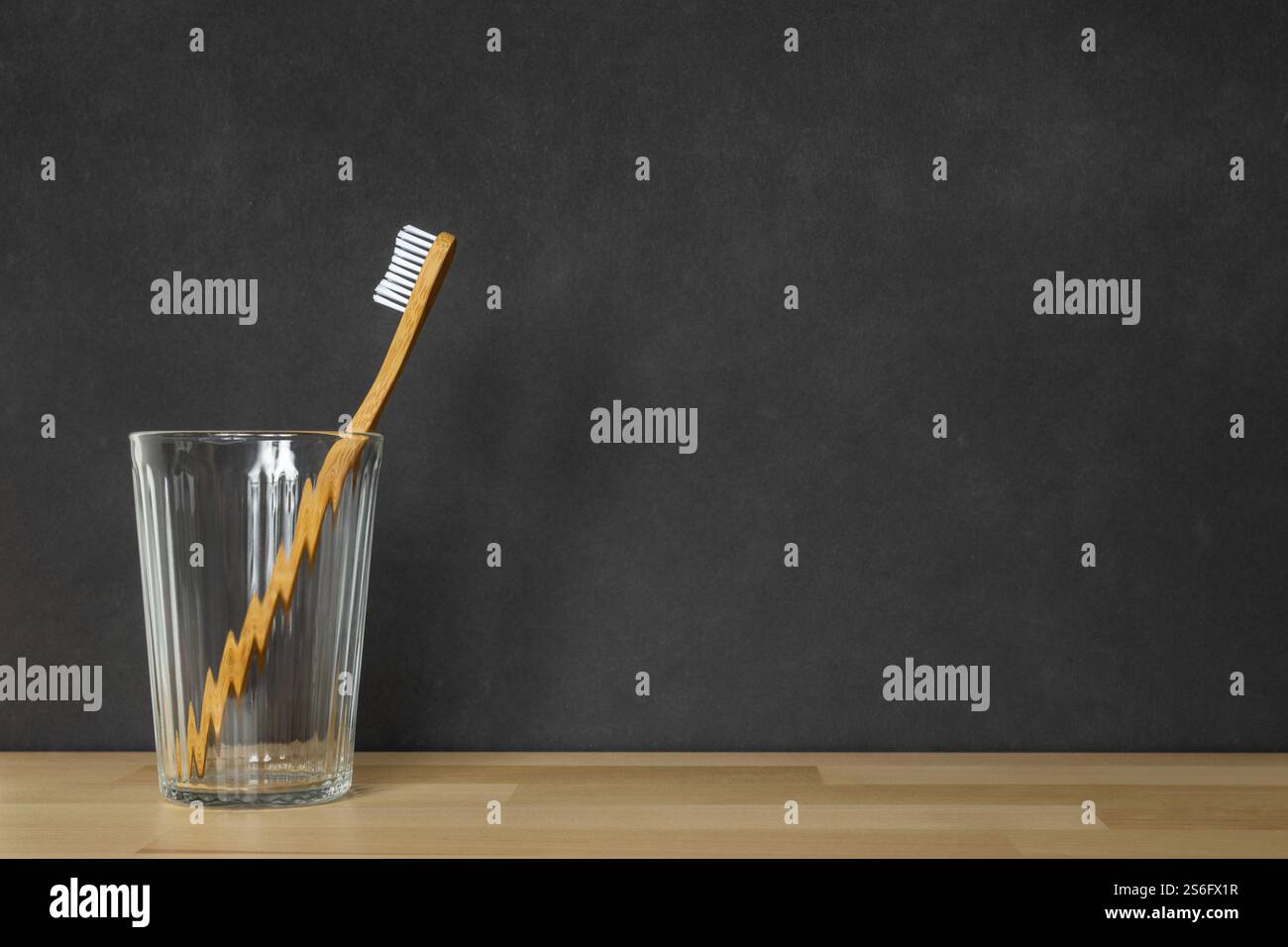 Ein Bild einer hölzernen Zahnbürste in einem Glas auf schwarzem Hintergrund Stockfoto