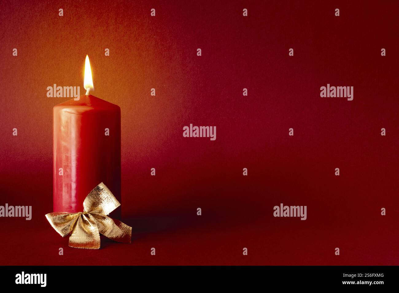 Weihnachtsdekoration mit einer brennenden Kerze auf rotem Hintergrund Stockfoto