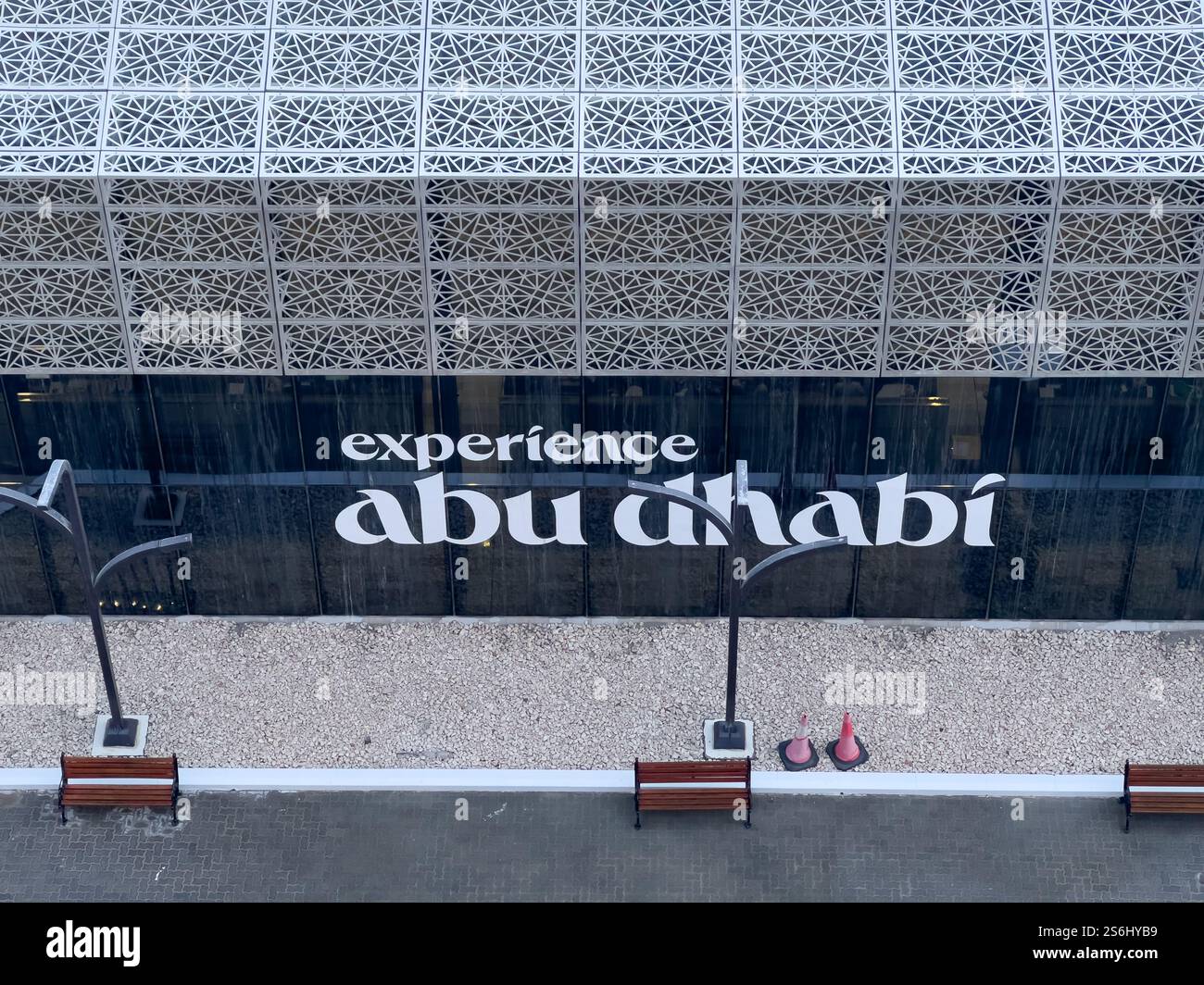 Abu Dhabi, VAE - 3. Januar 2025: Eine moderne Fassade mit komplizierten Mustern und einem auffälligen Schild, das Besucher einlädt, Abu Dhabi zu erleben. Stockfoto