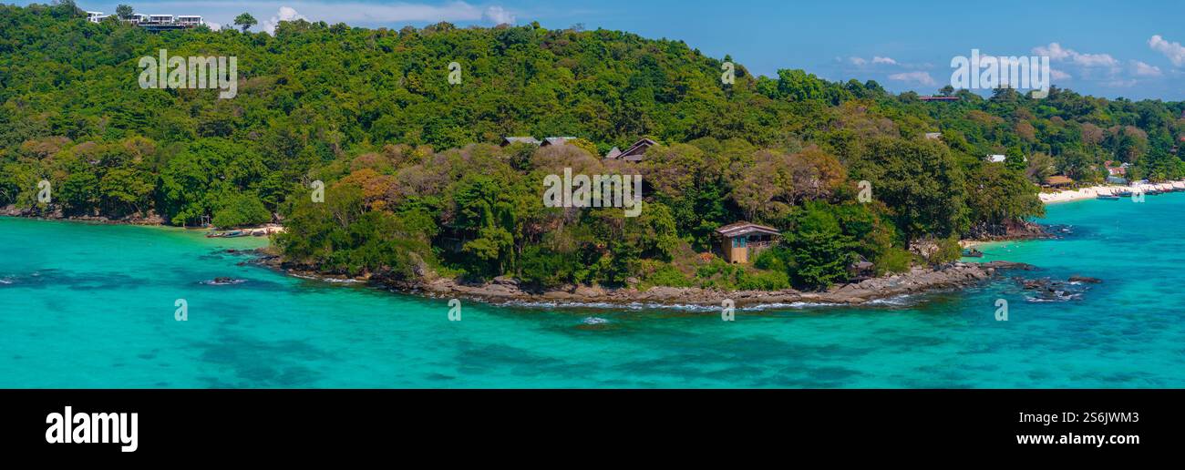 Üppige bewaldete Insel mit Sandstrand und Booten in Thailand Stockfoto