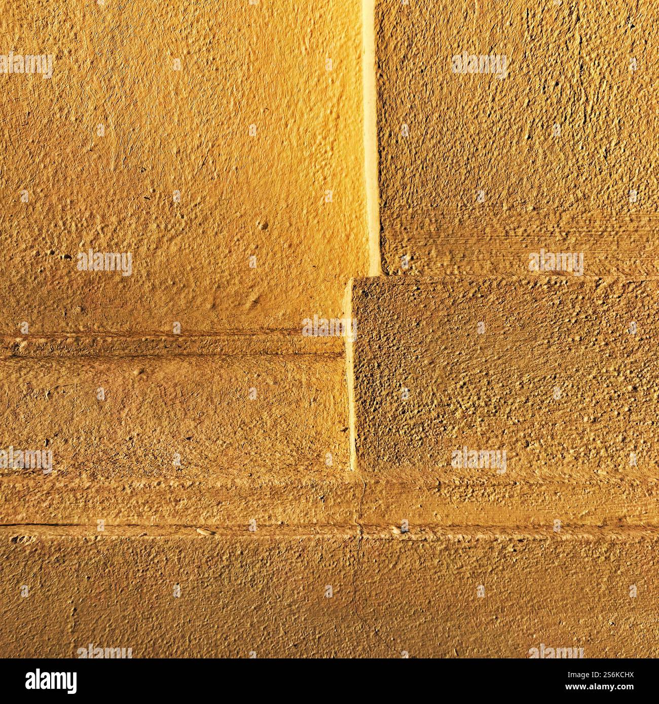 Gelb strukturierte Wand mit geometrischen Mustern und klaren Linien, die atemberaubende Einfachheit und Farbenpracht bieten. - Smartphone-aufgenommenes Stockfoto