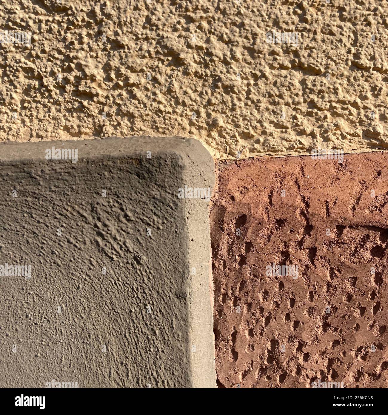 Detailliertes Bild, das die Verbindung verschiedener Wandstrukturen zeigt und Baumaterialien und Oberflächenkontraste unter natürlichem Sonnenlicht veranschaulicht. - Smartphone-aufgenommenes Stockfoto