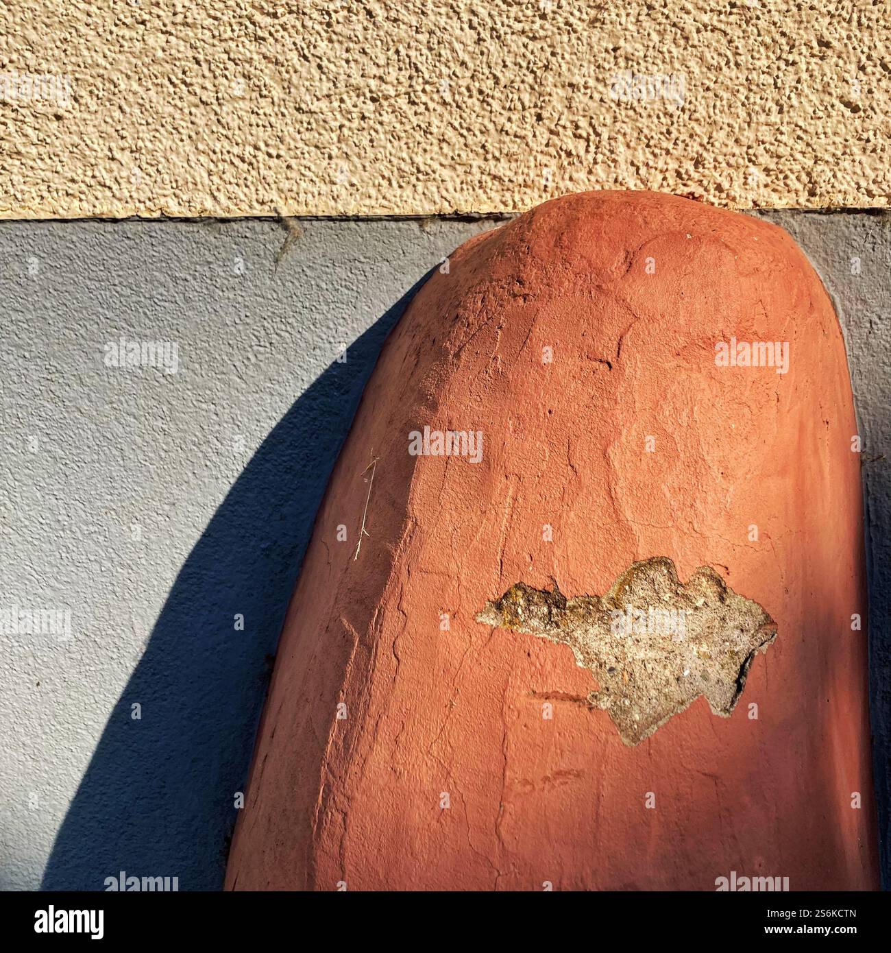 Nahaufnahme eines alten Steinpfollers vor einer strukturierten Wand mit Texturen und Details im Sonnenlicht Stockfoto
