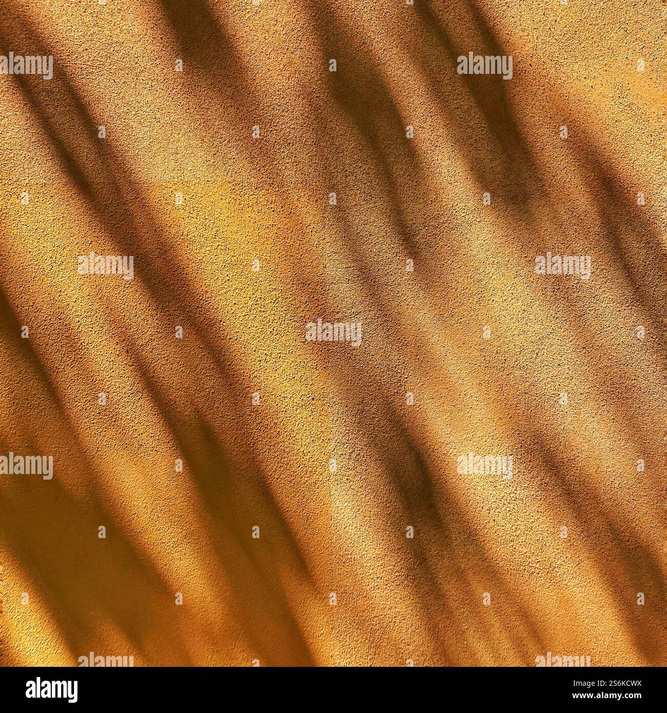 Abstrakte, goldfarbene Textur mit einem weichen Zusammenspiel von Schatten und Lichtmustern, die Wärme, Eleganz und ein Gefühl natürlicher Schönheit wecken. Stockfoto