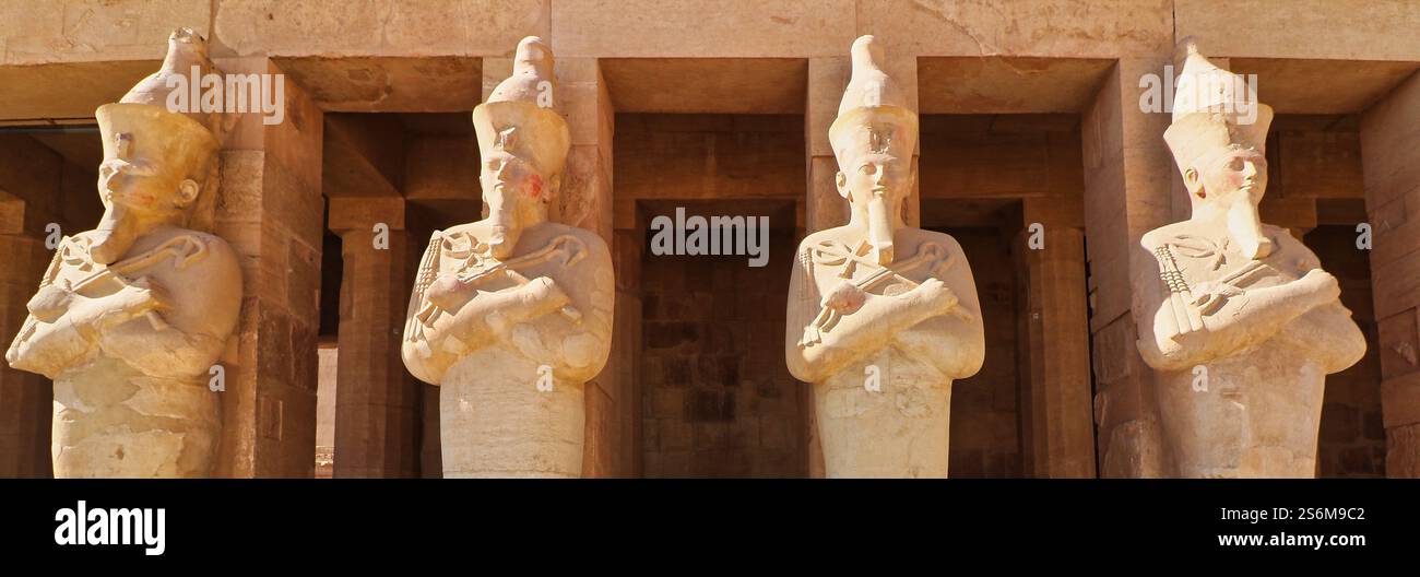 Massive Statuen der großen weiblichen Pharoah Hatschepsut in Sandstein gemeißelt dominieren die äußeren Säulen des Leichentempels in Deir Al Bahari, Luxor, Ägypten Stockfoto
