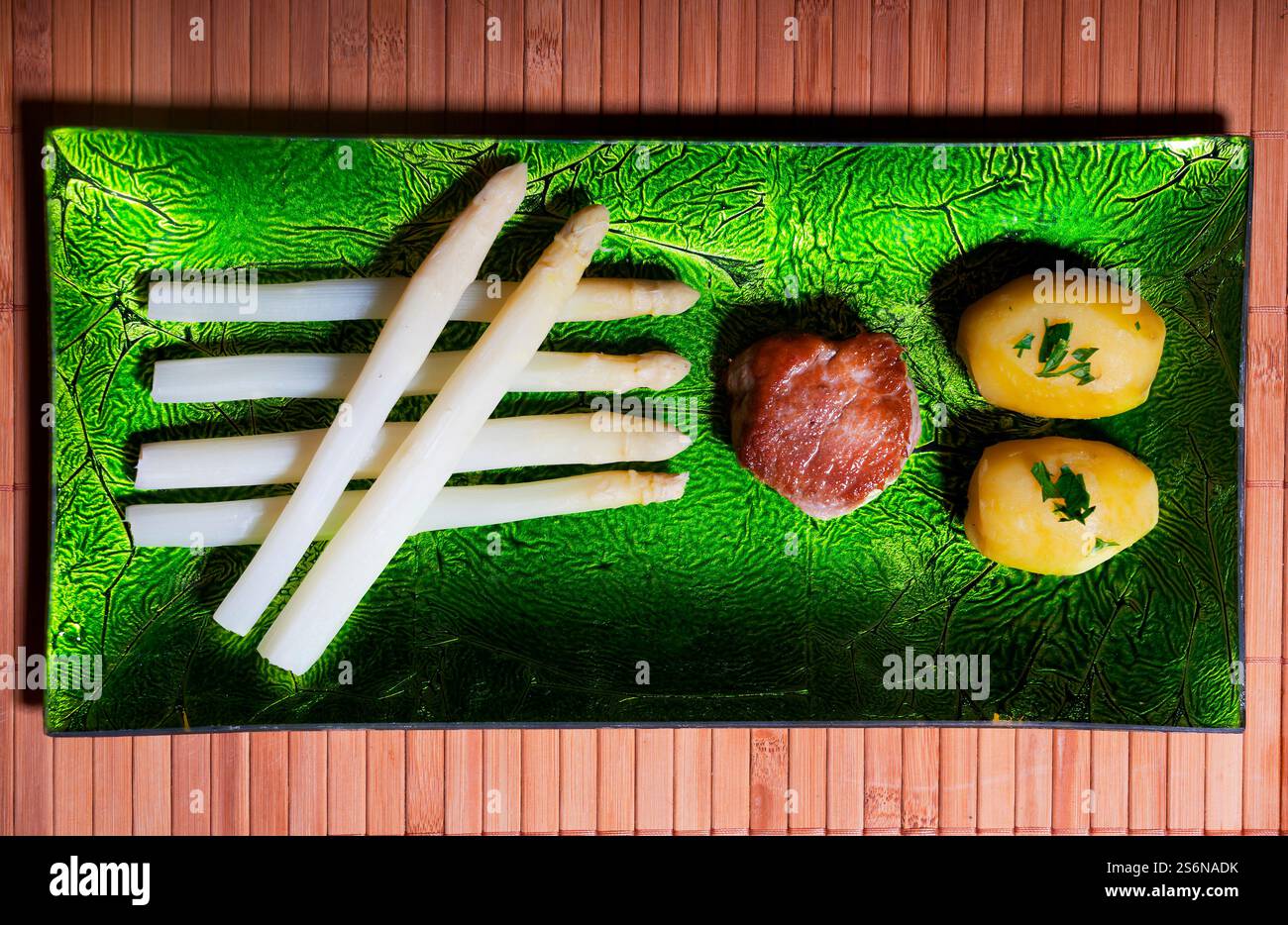 Geschälter weißer Spargel auf einer grünen Platte Stockfoto