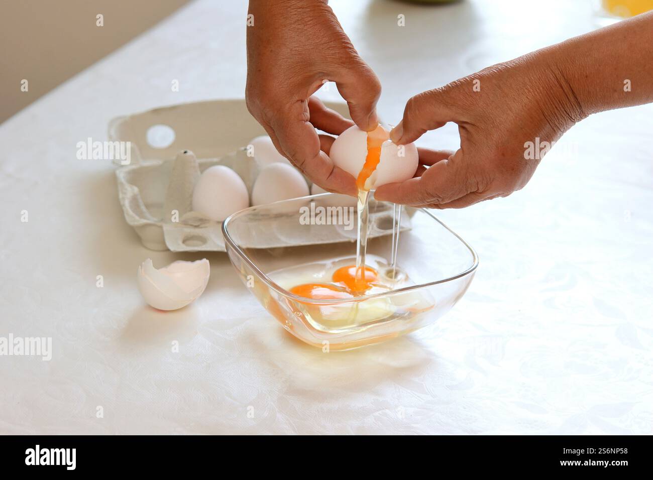 Eine Frau knackt Eier in eine Schüssel Stockfoto