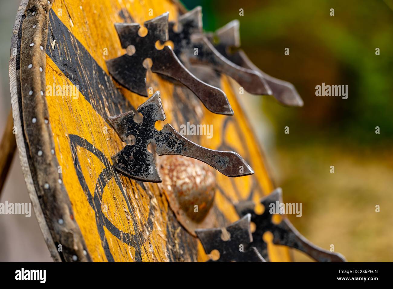 Eine Gruppe von Äxten hängt an einem Holzschild. Der Schild ist gelb und hat ein Kreuz Stockfoto