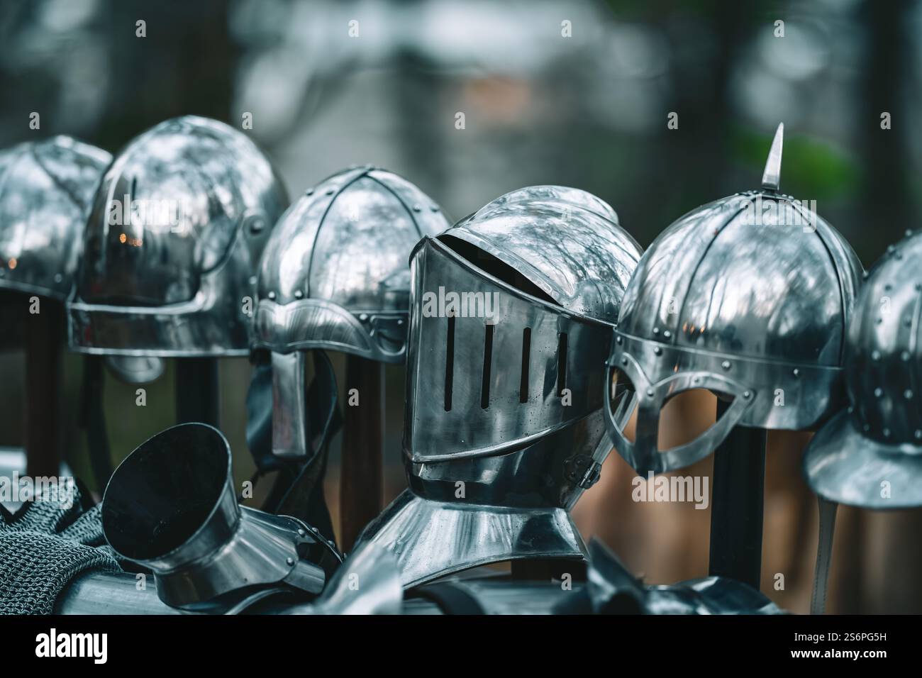 Eine Reihe von Helmen stehen auf der Reihe, von denen einige Schilde tragen. Die Helme sind alle aus Silber und scheinen aus einer mittelalterlichen Zeit zu stammen Stockfoto