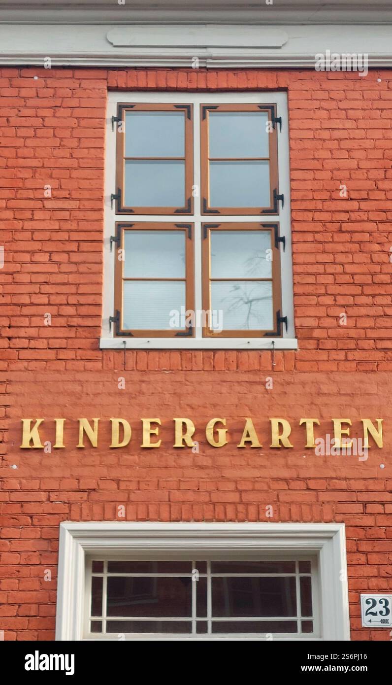 Goldener „Kindergarten“-Schriftzug auf roter Ziegelfassade mit Stufenfenstern Stockfoto