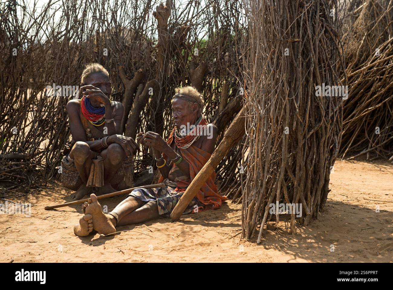 Zwei alte Frauen sitzen vor einem Zaun aus Holzstäben und kleinen Baumstämmen, Karo-ethnische Gruppe, Süd-Omo-Tal, Süd-Äthiopien Stockfoto