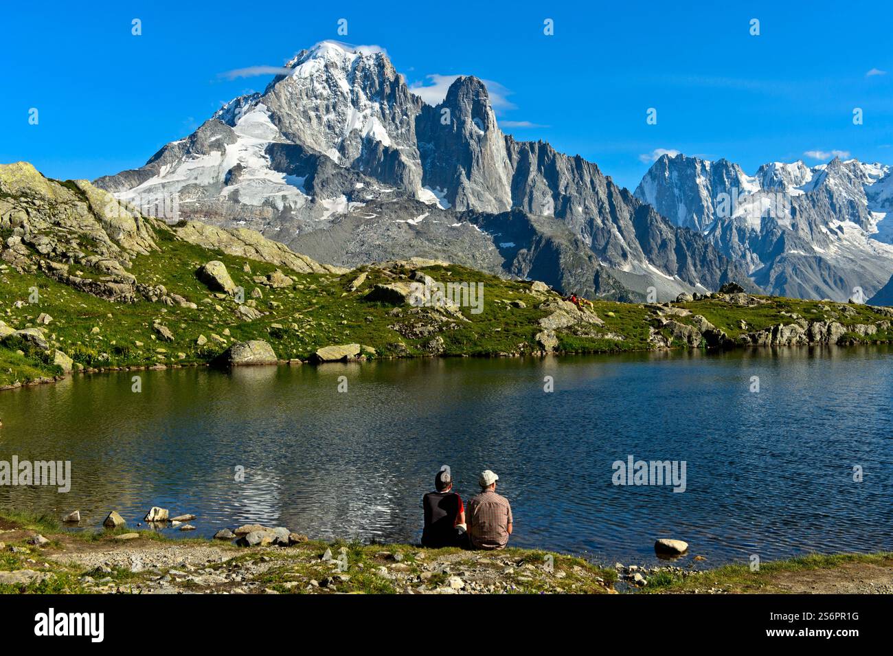 Wanderer ruhen am Lacs des Cheserys Bergsee im Naturschutzgebiet Aiguilles Rouges, mit den Gipfeln Aiguille Verte und Aiguille du Dru dahinter, Chamonix, Haute Savoie, Frankreich Stockfoto
