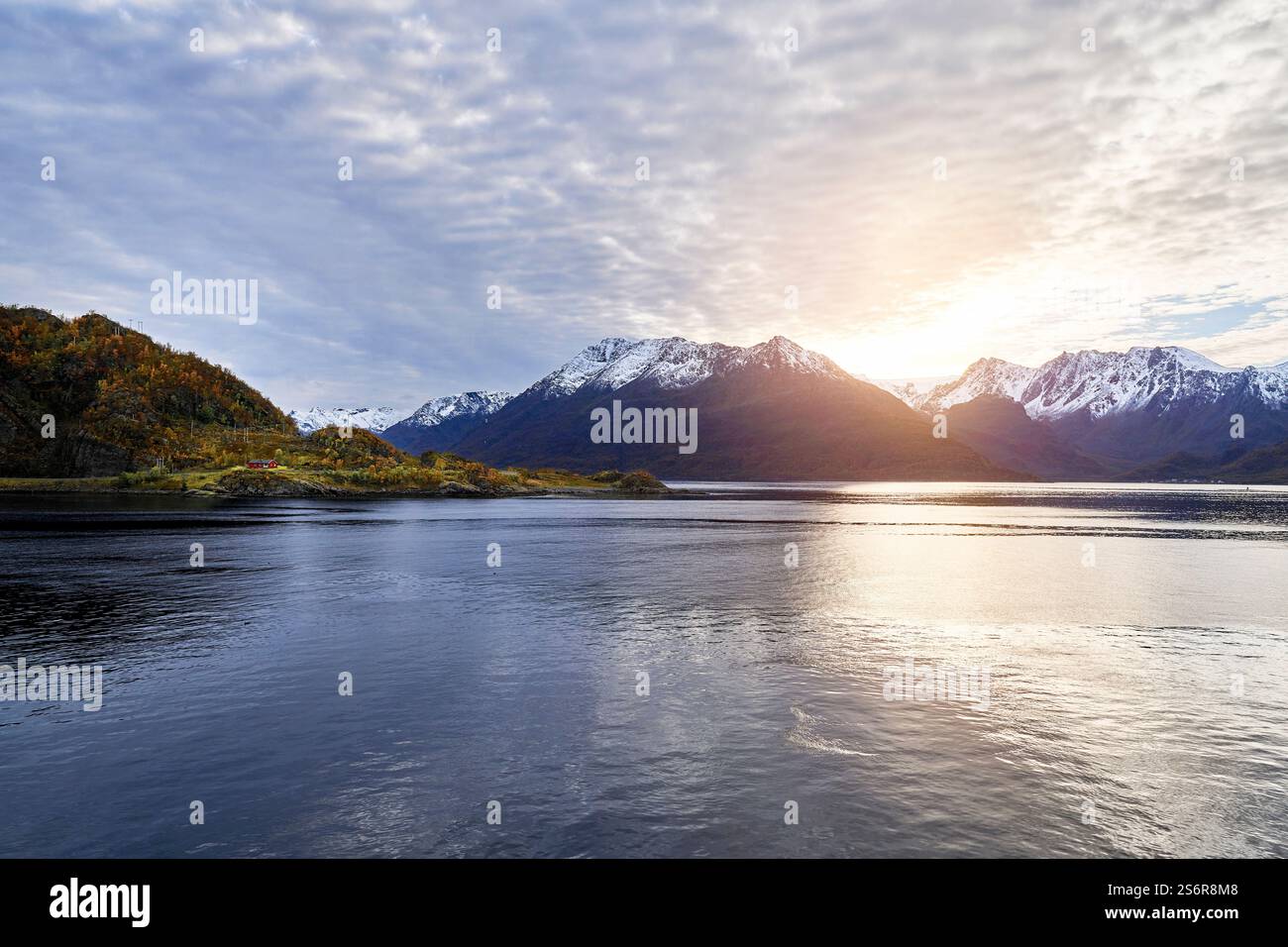 Fahren Sie an der Küste Norwegens, der Halbinsel Bergsfjord in der Nähe von Oksfjord mit der Gletscherkrone von Oksfjordjokelen, die von der Sonne beleuchtet wird Stockfoto