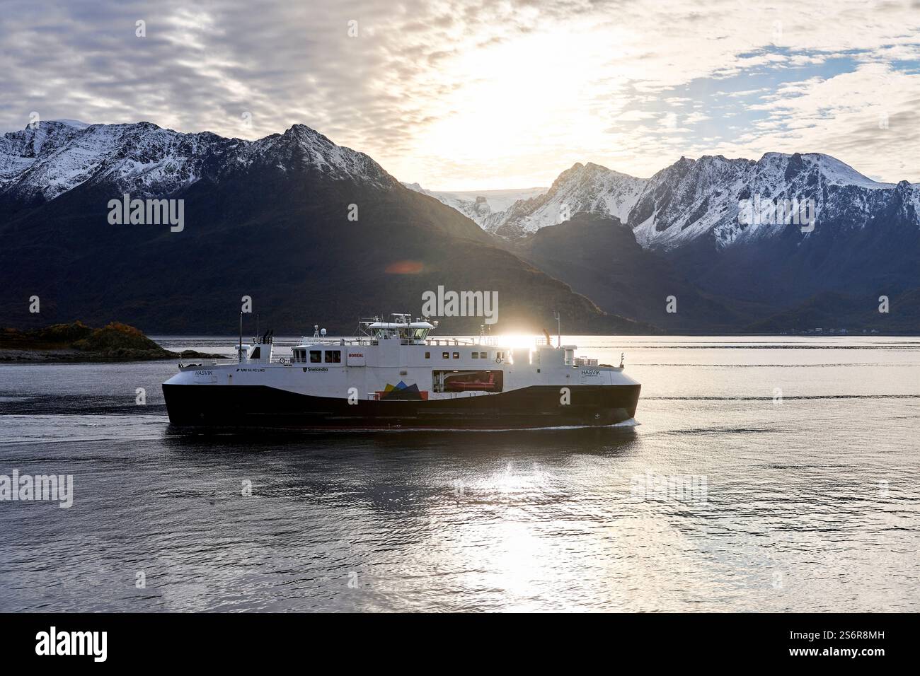 Fahren Sie an der Küste Norwegens, der Halbinsel Bergsfjord in der Nähe von Oksfjord mit der Gletscherkrone Oksfjordjokelen, einem von der Sonne beleuchteten Fährschiff Stockfoto
