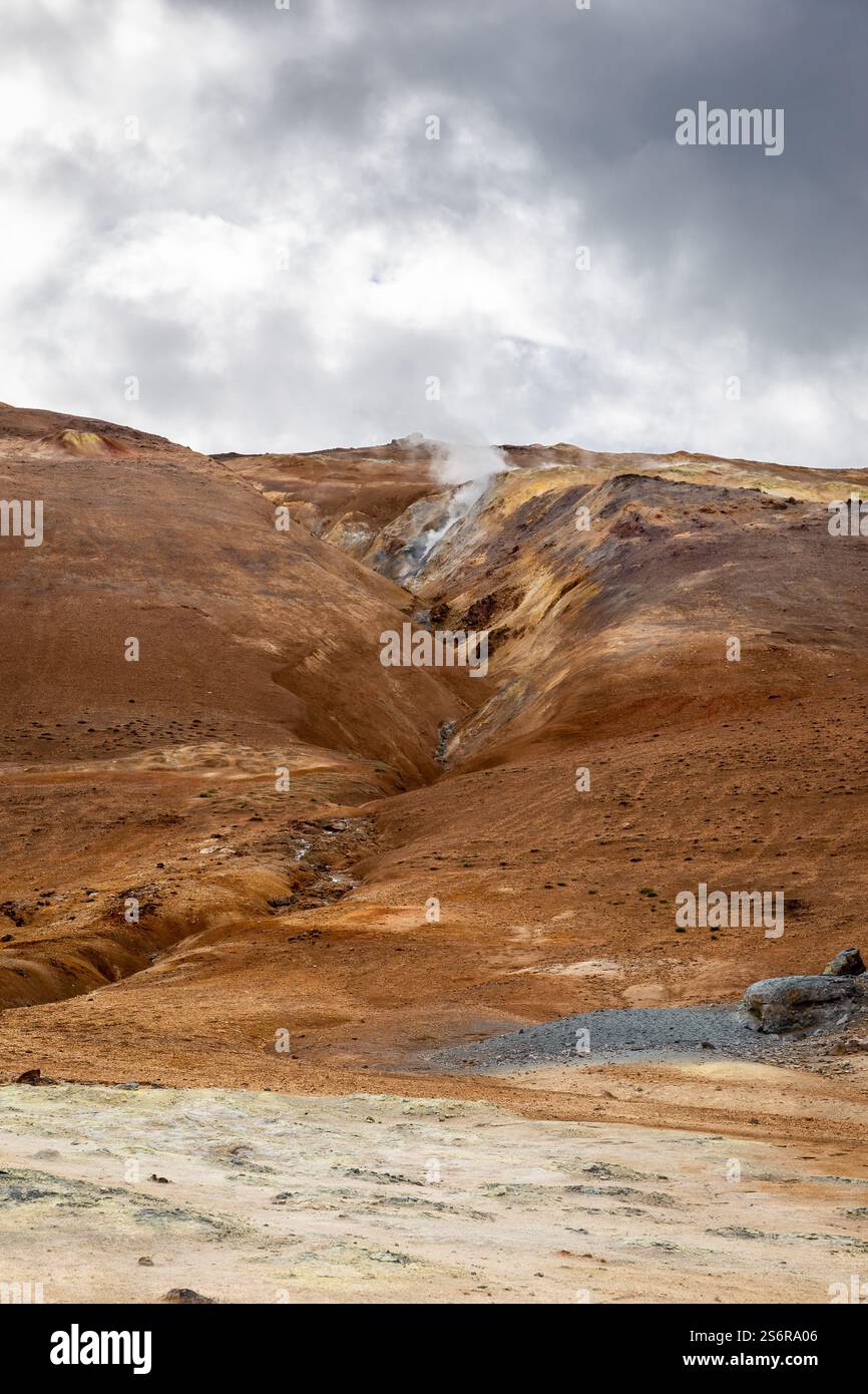 Vulkanische Landschaft von Hverir, Myvatn geothermisches Gebiet in Island, mit Rissen, dampfenden heißen Quellen und orangen Mineralböden und Felsen. Stockfoto