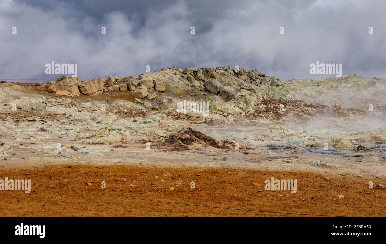 Vulkanische Landschaft von Hverir, Myvatn geothermisches Gebiet in Island, mit dampfenden heißen Quellen und orangen Mineralböden und Felsen. Stockfoto