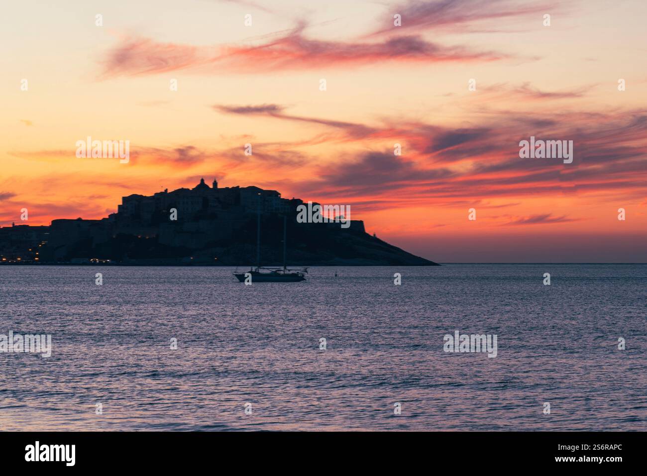 Die Altstadt von Calvi auf der französischen Insel Korsika bei Sonnenuntergang. Die Sonne geht hinter der Zitadelle unter. Stockfoto