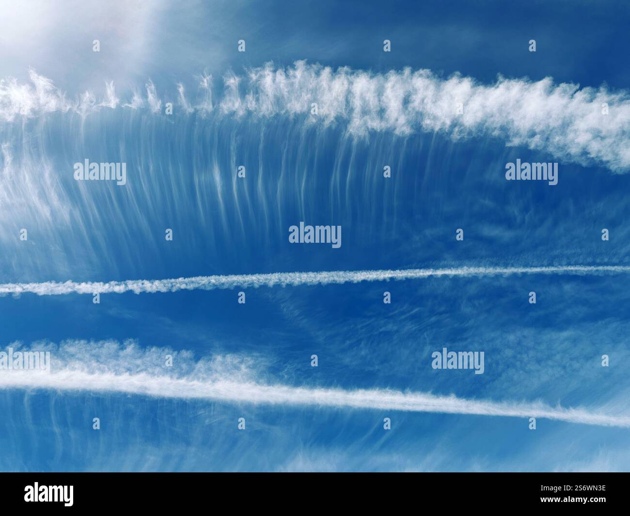 Eine Reihe von drei Kondensationsspuren in einem blauen Himmel. Stockfoto