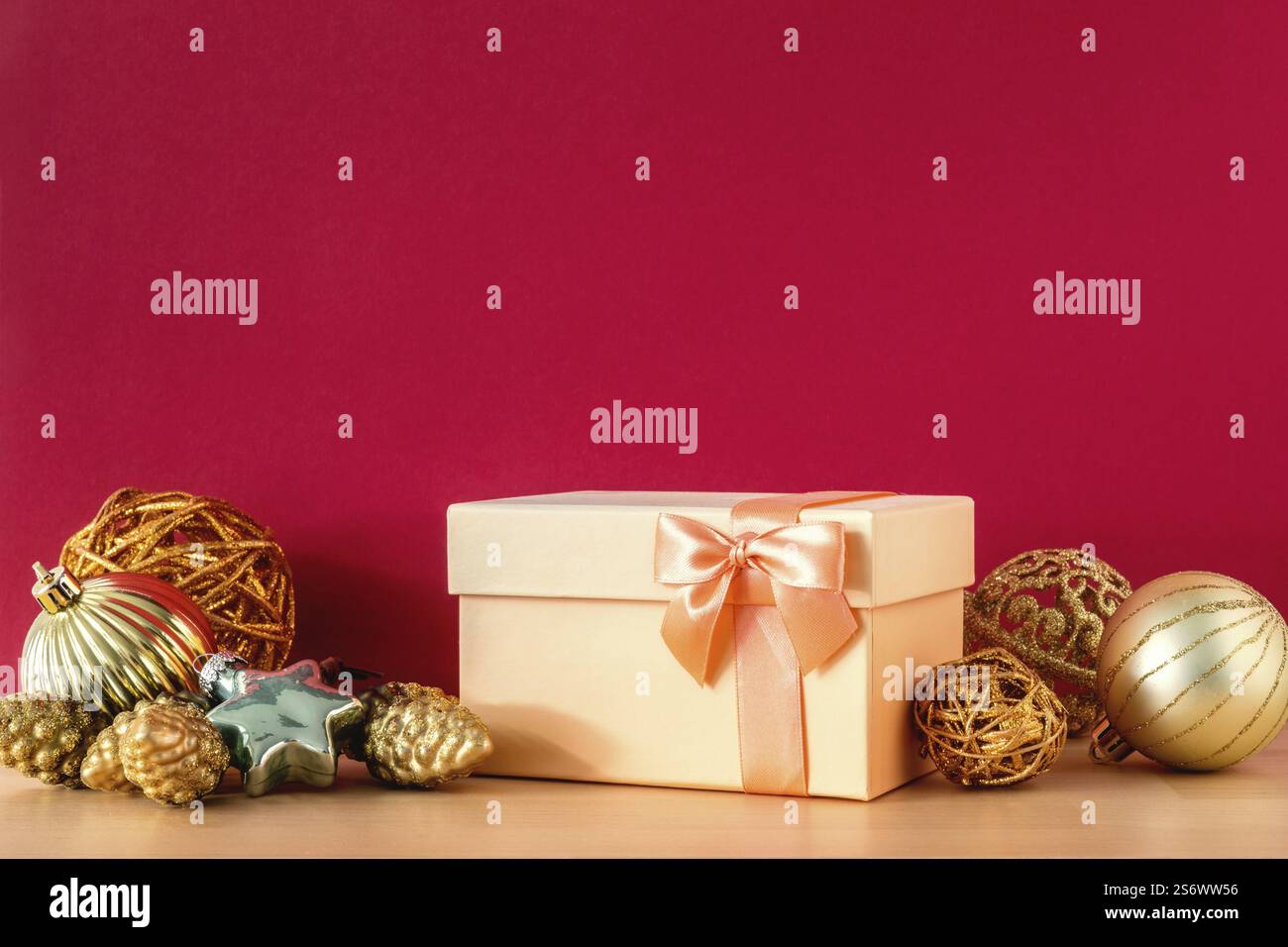 Eine goldene Weihnachts-Geschenkbox auf rotem Hintergrund Stockfoto