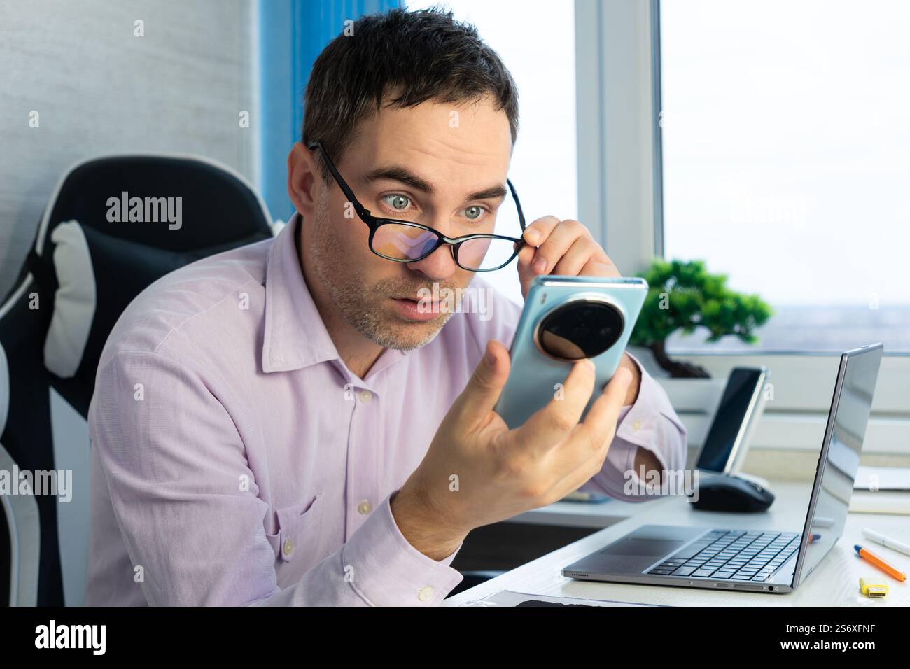 Der kahlköpfige Junge sah sehr überrascht aus, als er seinen Smartphone-Bildschirm, seine Werbung und seinen Kopierraum sah. Stockfoto