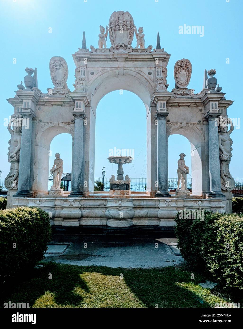 Der majestätische Fontana del Gigante in Neapel, Italien – ein großer barocker Brunnen mit komplizierten Skulpturen und einem Bogen, der das Meer umrahmt. Stockfoto