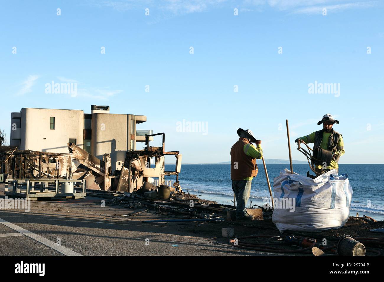 Los Angeles, Usa. Januar 2025. Ein Haus, das durch den Lauffeuer von Palisades und zwei Arbeiter zerstört wurde, die den Schutt in der Nähe von will Rogers States Beach räumten. Katastrophengebiete im Stadtteil Pacific Palisades nach dem Waldbrand, der am 7. Januar 2025 in Los Angeles in den Santa Monica Mountains ausbrach. Foto: Christophe Michel/ABACAPRESS. COM Credit: Abaca Press/Alamy Live News Stockfoto